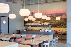 Un restaurant moderne décoré de lanternes en papier suspendues, avec un buffet proposant des produits frais et une fresque représentant un paysage urbain en arrière-plan.
