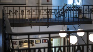 A multi-level interior with a staircase, black railings, and pendant lighting.