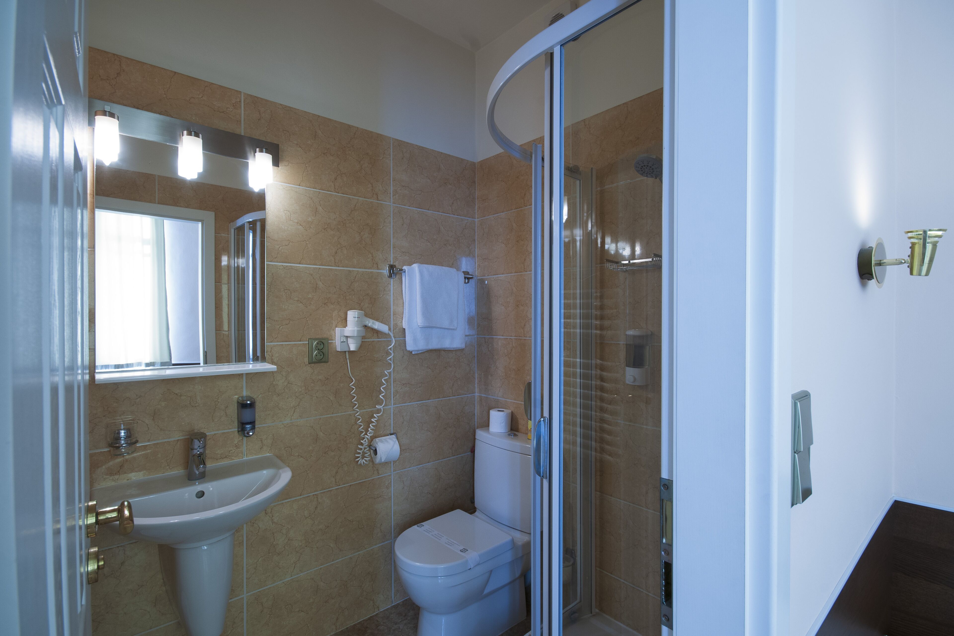 Un baño con lavamanos, inodoro y ducha con mampara de vidrio.