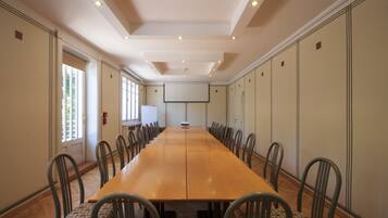 A conference room with a long table, chairs, a projector screen, and a large window.