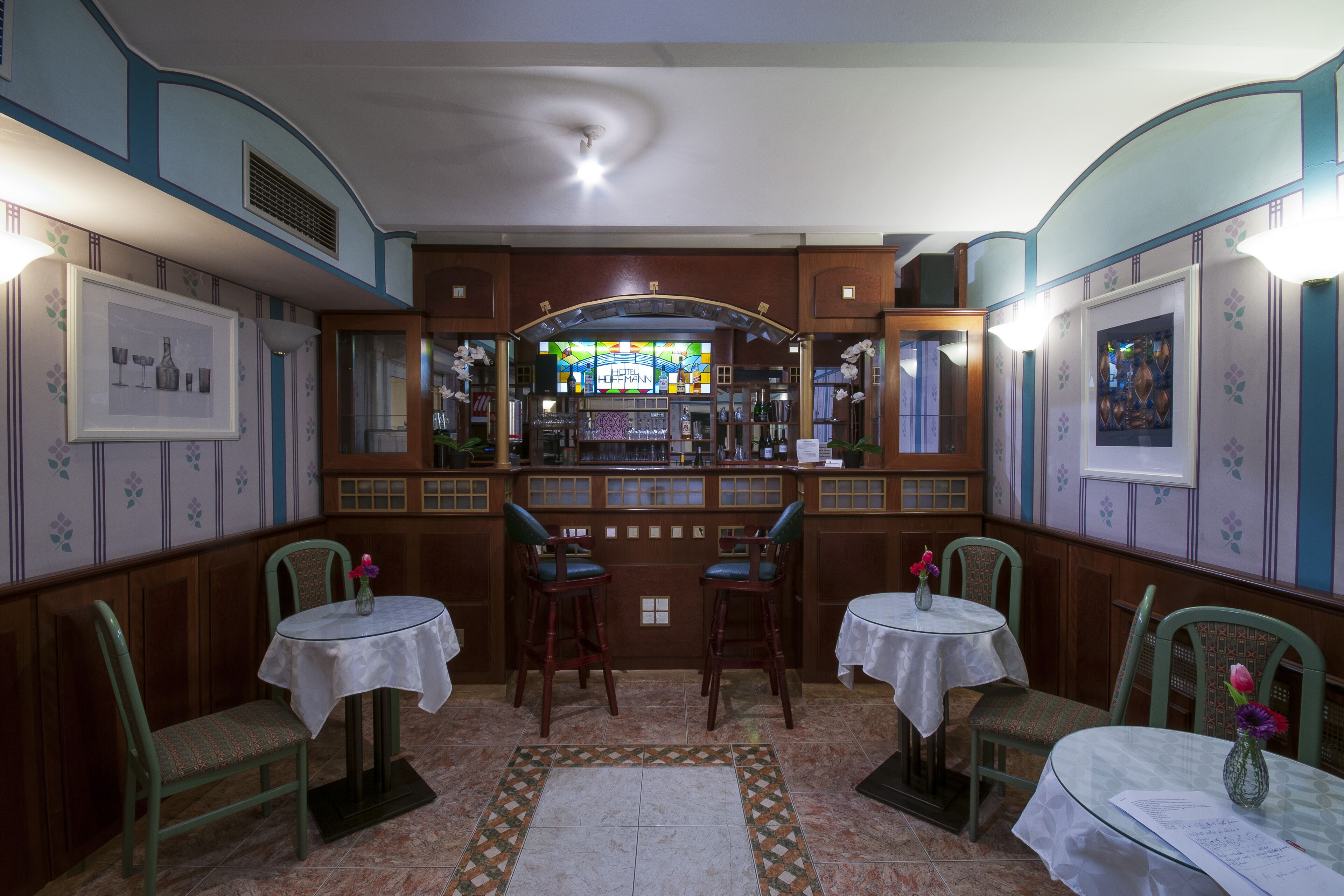Een bar met twee krukken, een bar en een decoratief glas-in-loodraam.