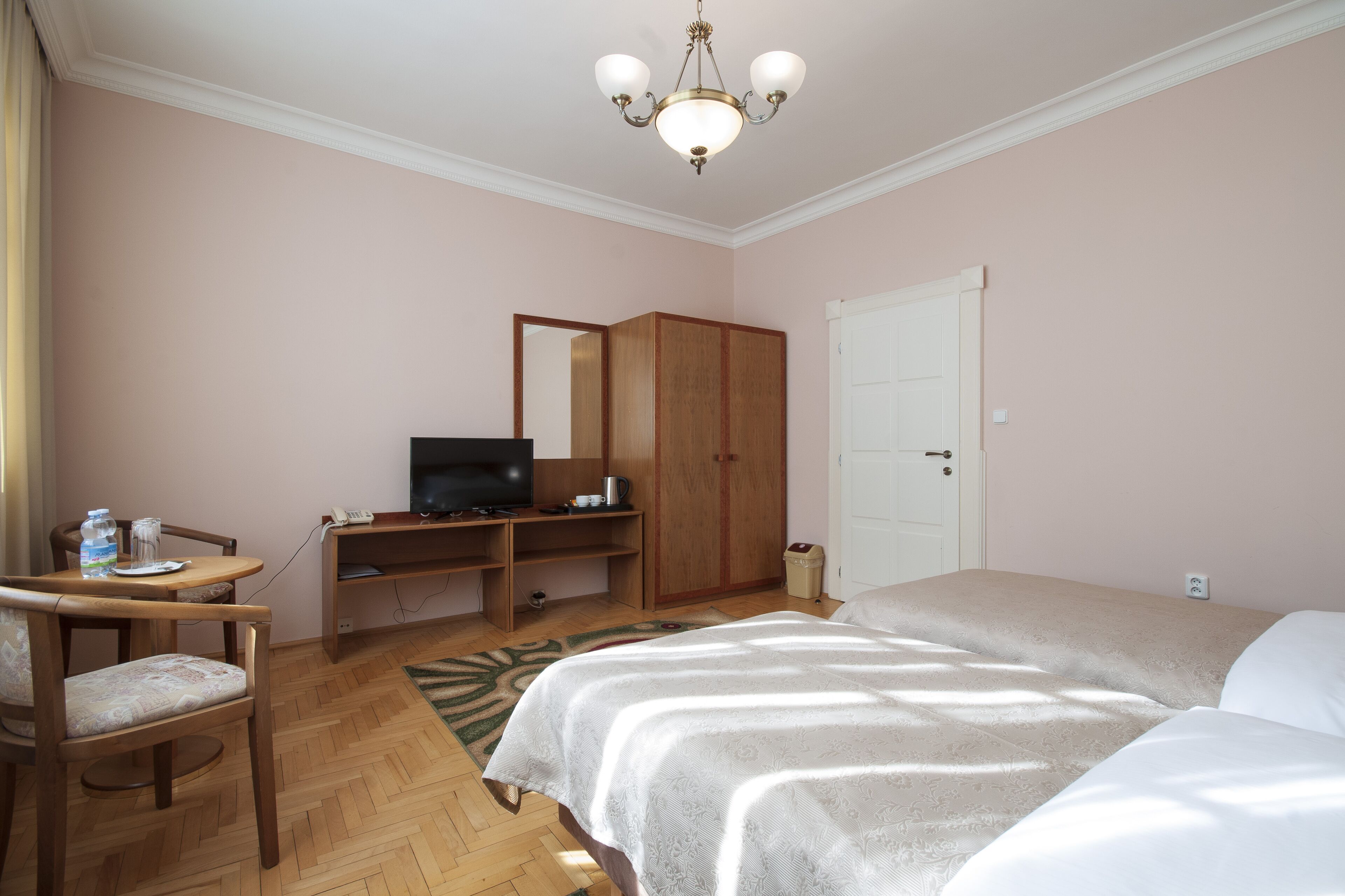 Un dormitorio con cama, escritorio con televisor, armario y una silla.