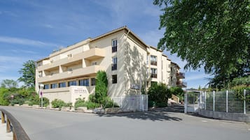 Un hotel de varios pisos con fachada color beige, balcones y un letrero que indica que es un hotel.