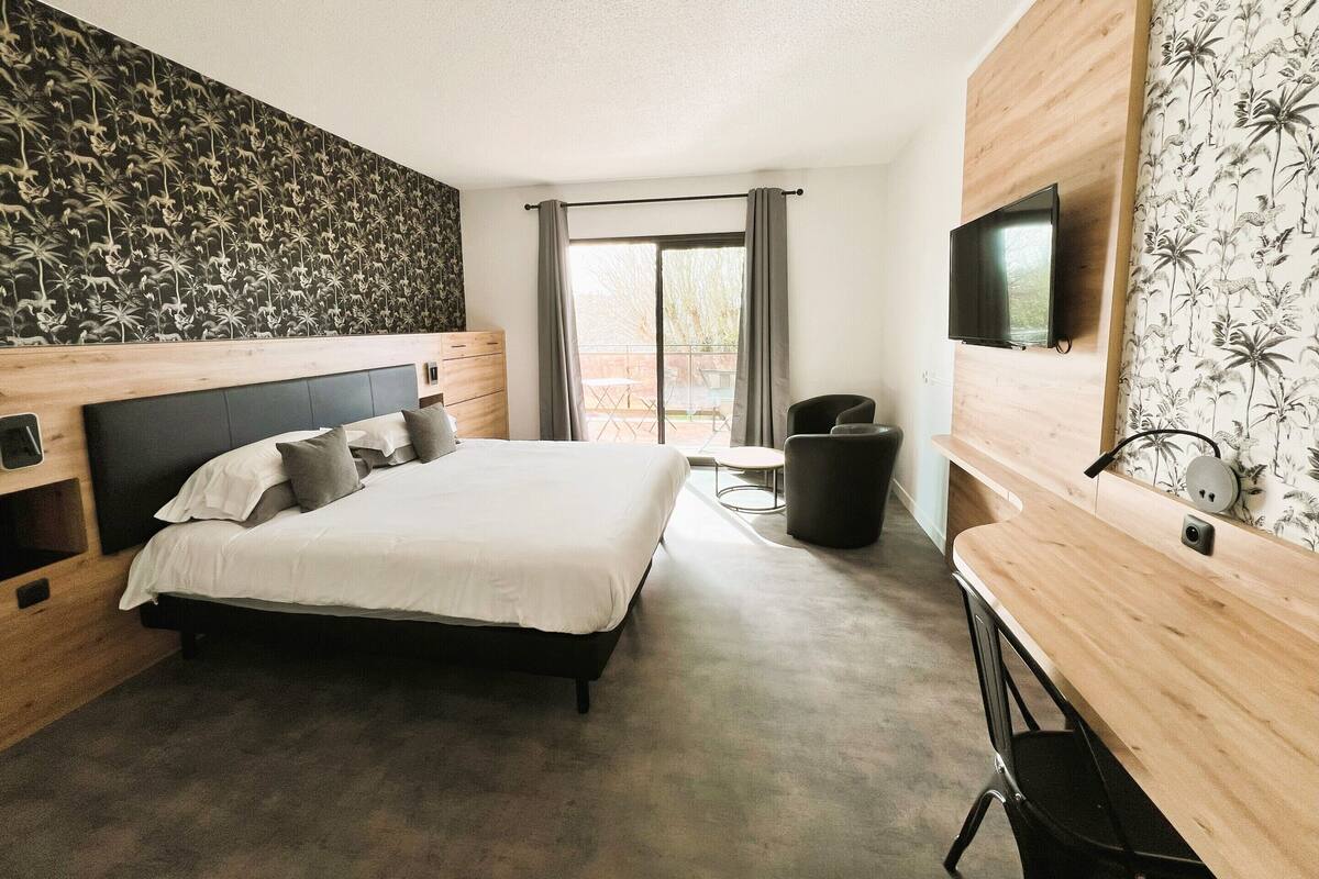 Une chambre d’hôtel moderne dotée d’un grand lit, d’un bureau, d’une télévision et d’un balcon avec vue.
