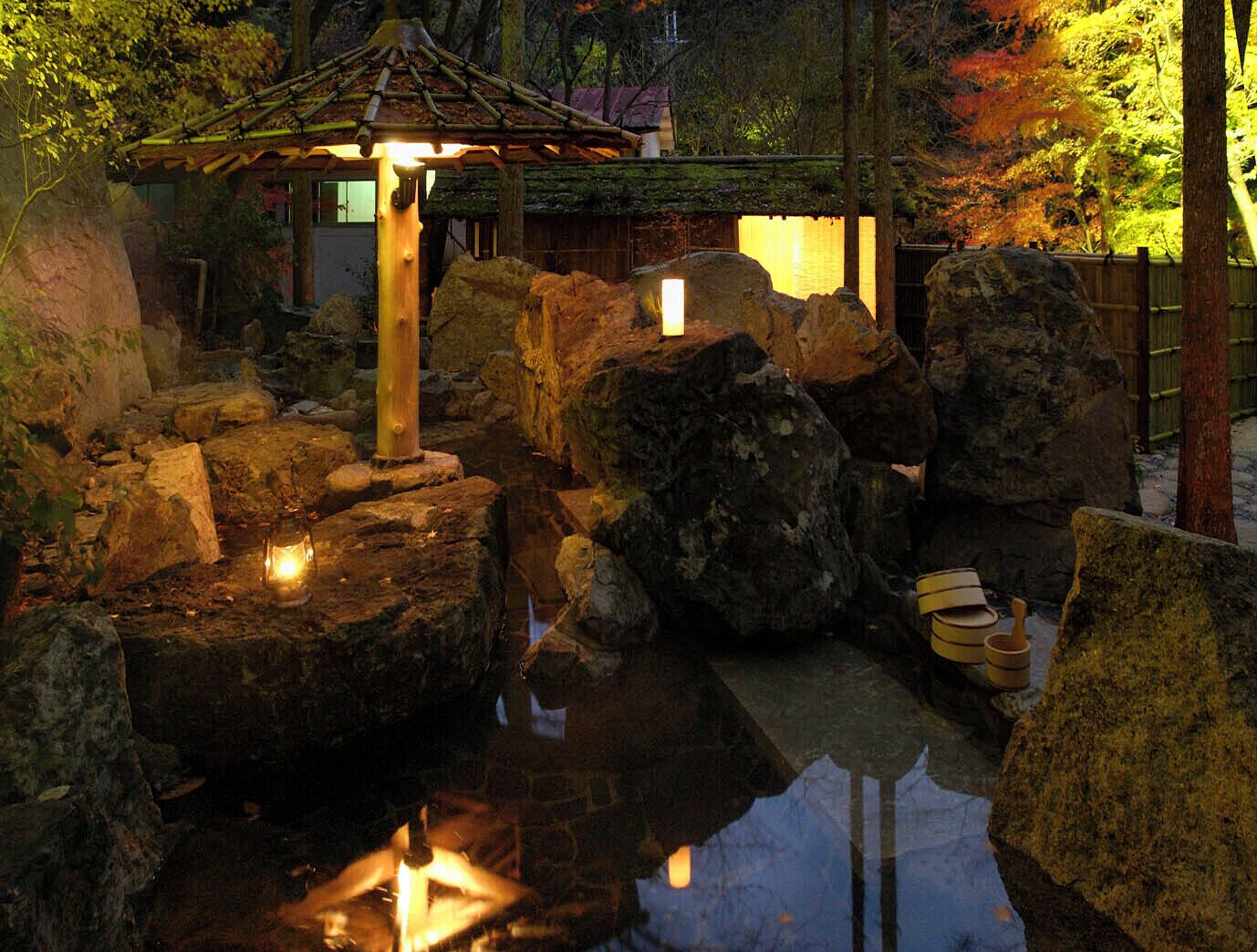 A tranquil garden with a traditional Japanese-style lantern, large rocks, and a small pond.