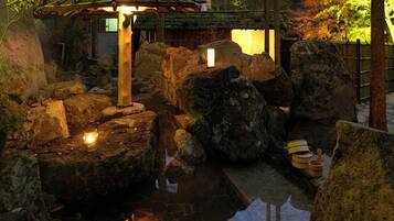 A tranquil garden with a traditional Japanese-style lantern, large rocks, and a small pond.