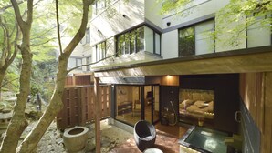 A modern building with a glass exterior, a wooden deck, a hot tub, and a seating area.