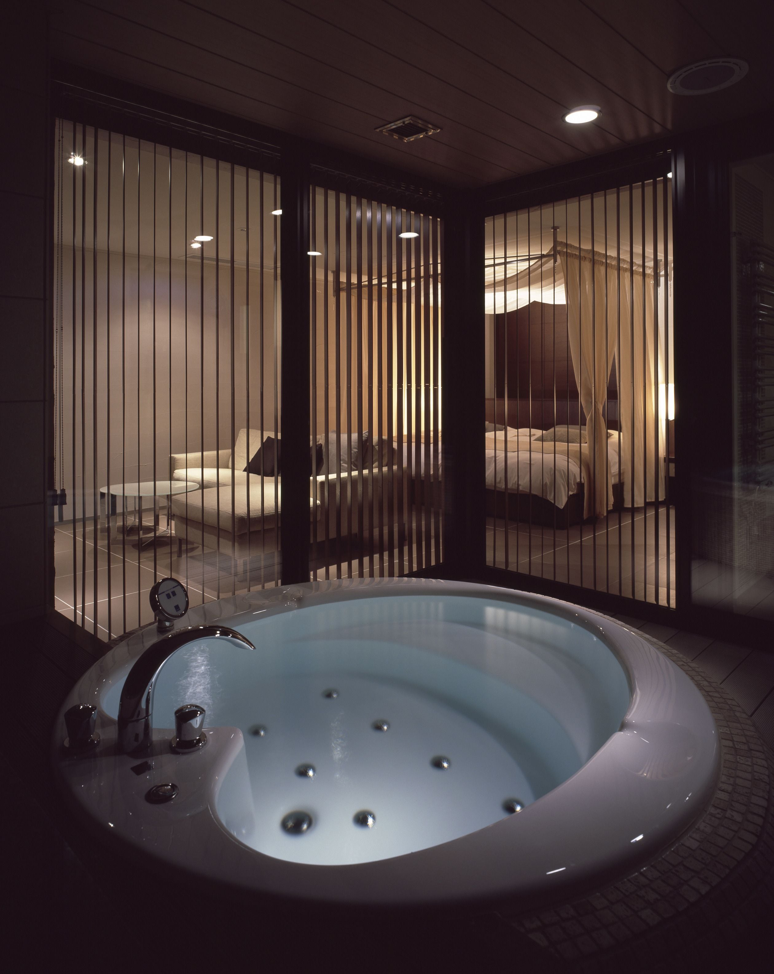 A spa room with a large bathtub, a small table, and a chair.