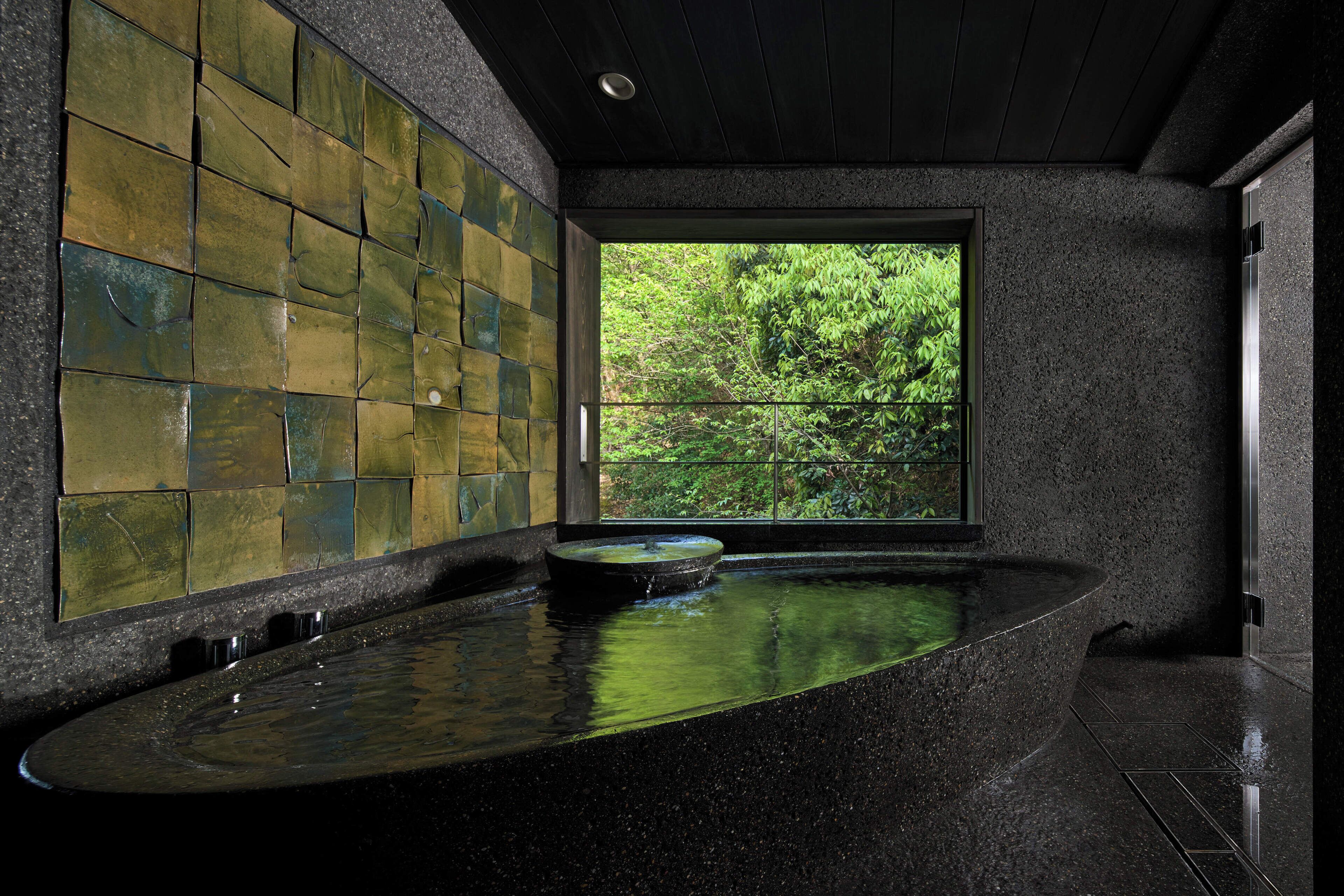 A modern bathroom with a large window, a curved sink, and a mosaic wall.
