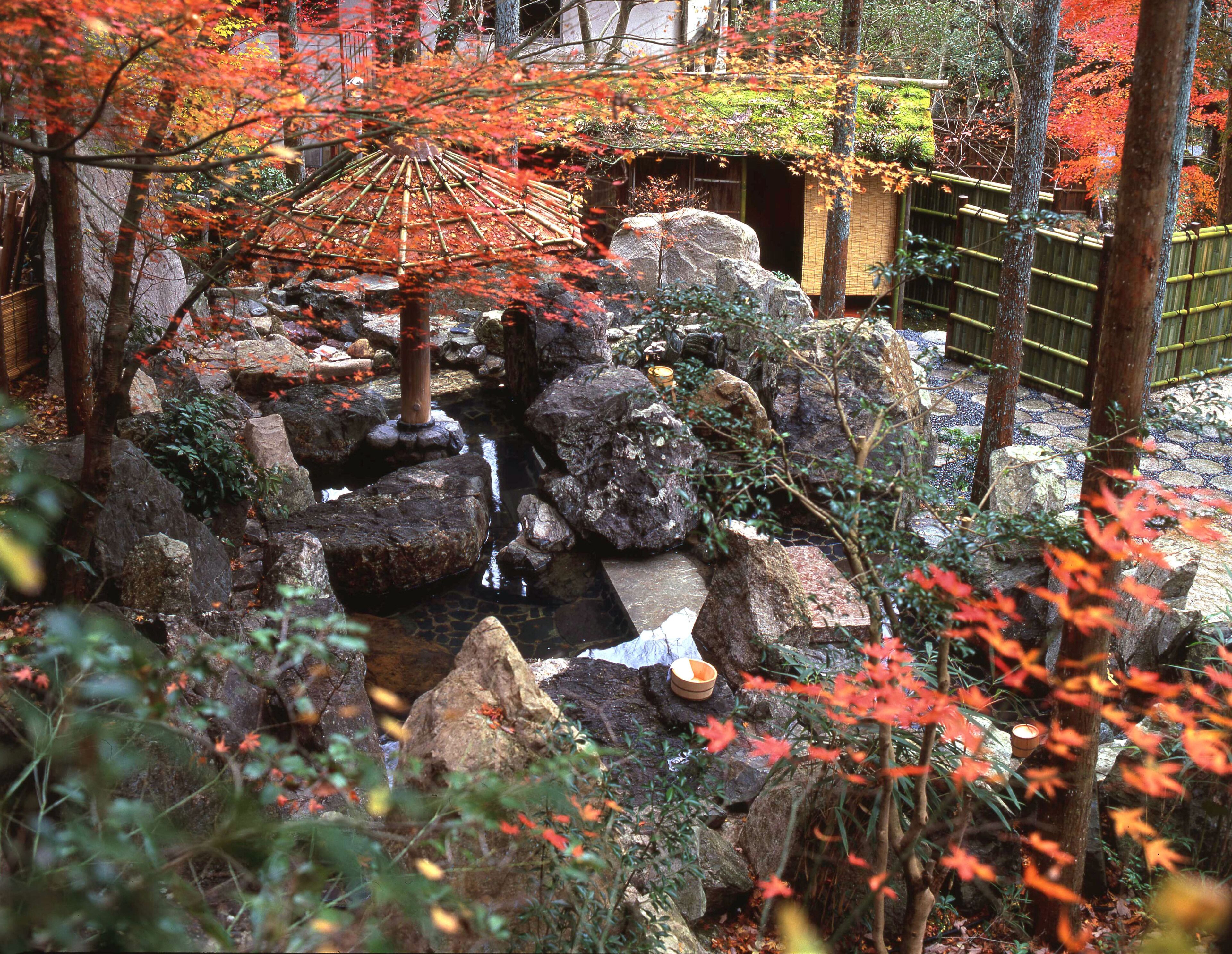 Um jardim japonês tradicional com um pequeno lago, pedras e folhagem de outono.