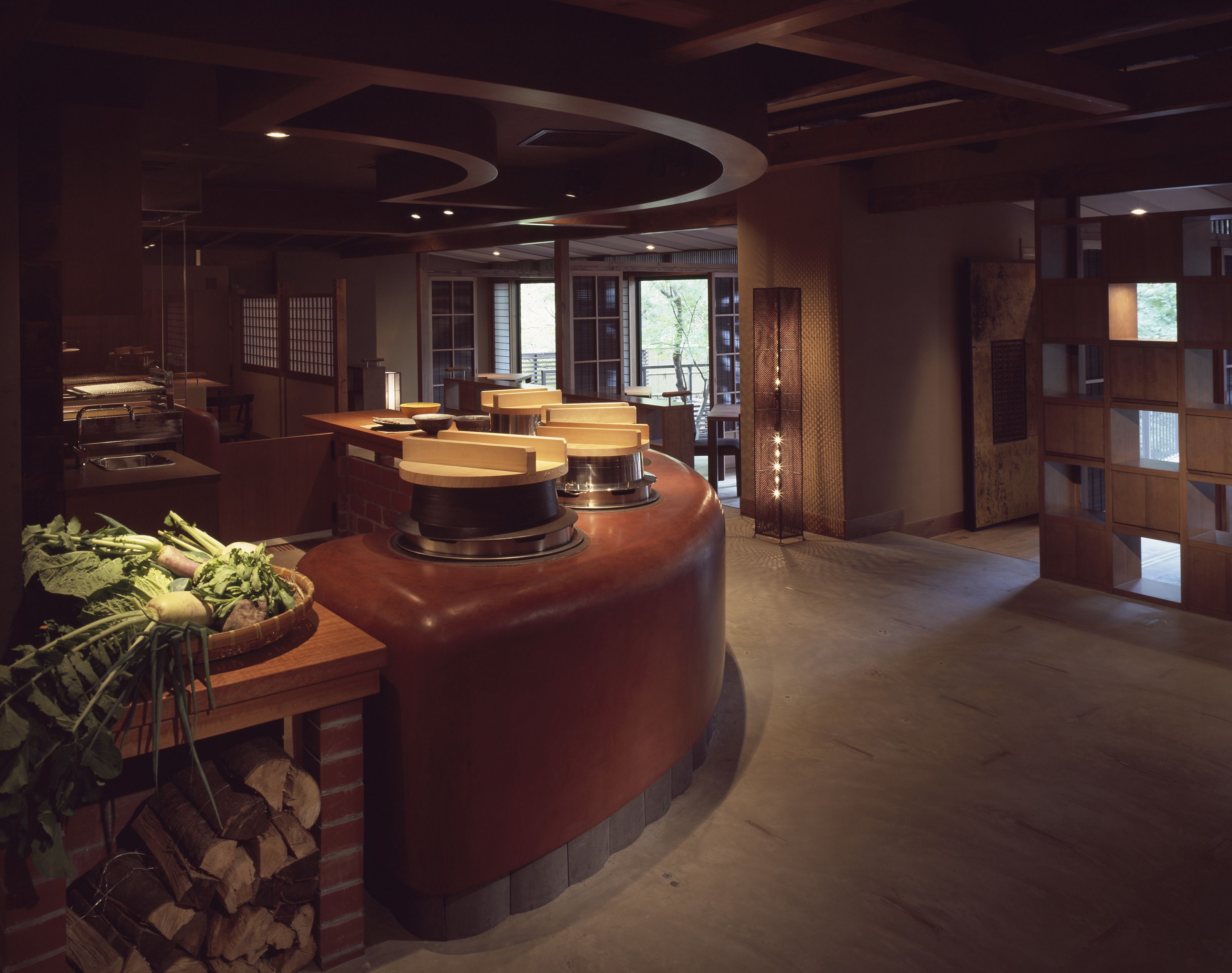 Une cuisine moderne avec un îlot central aux lignes courbes, des armoires en bois et un mur en briques.