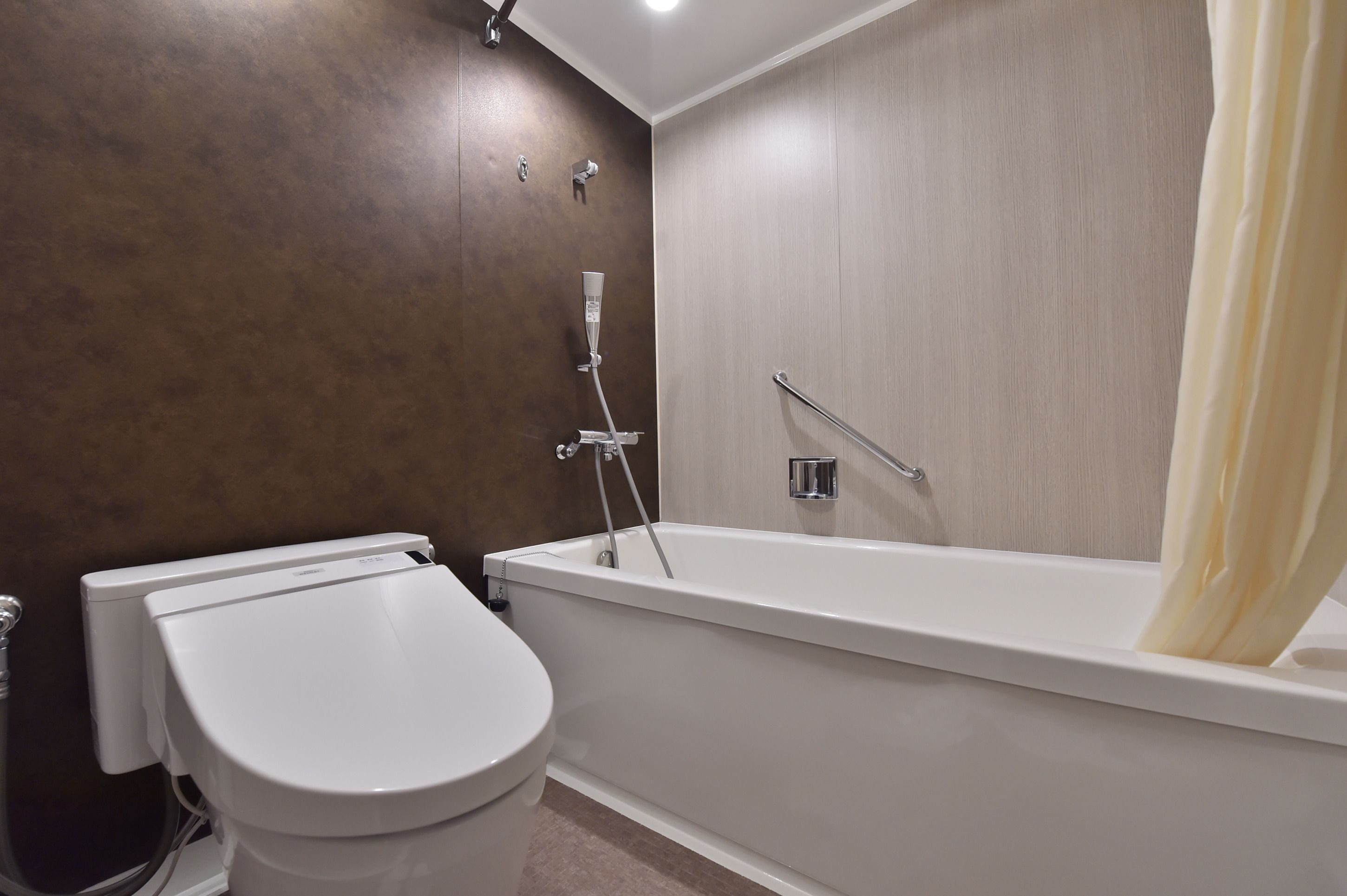 A modern bathroom with a white toilet, a bathtub, and a shower.