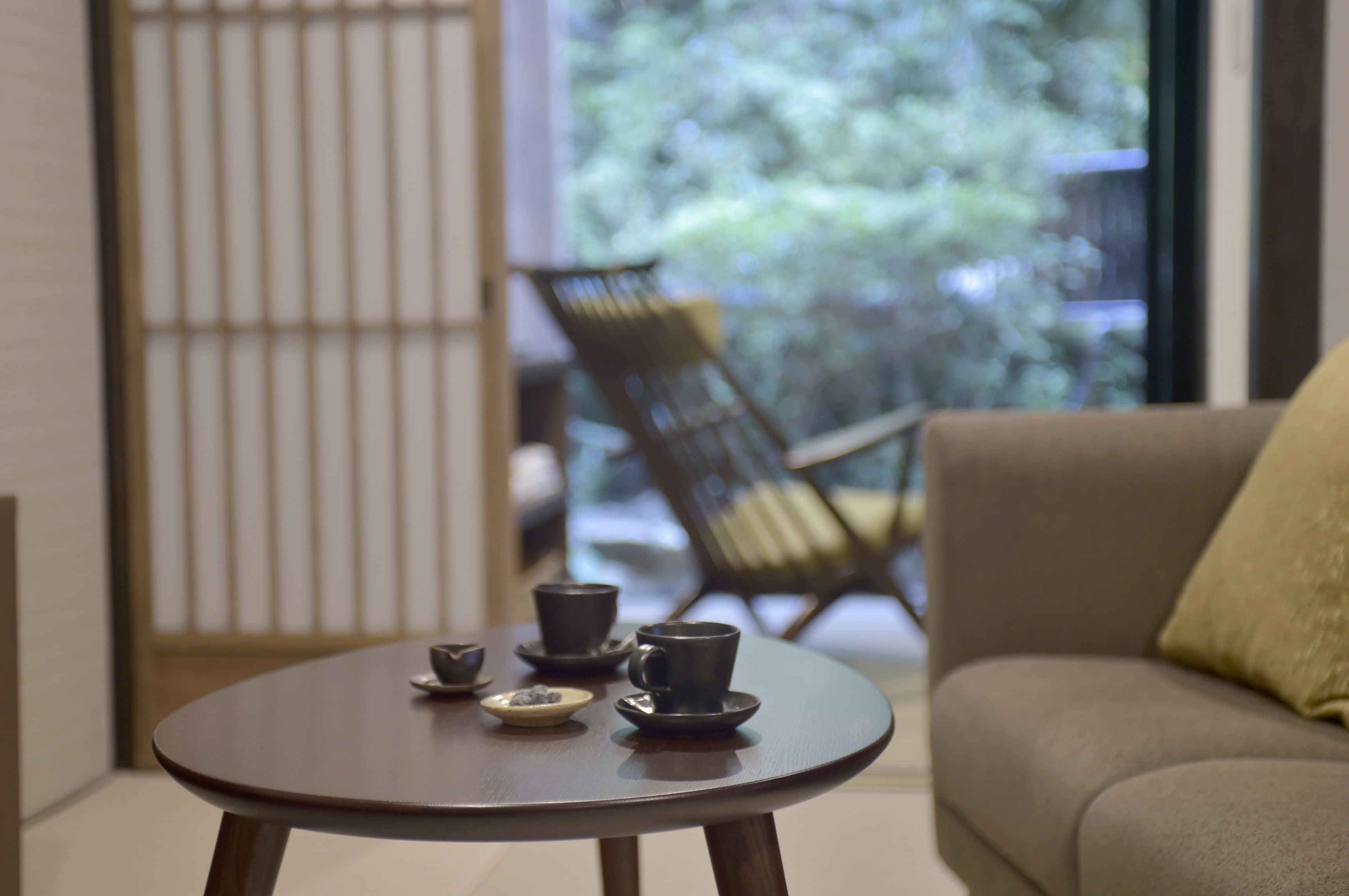 A room with a round table, a sofa, and a chair. There are three cups on the table.