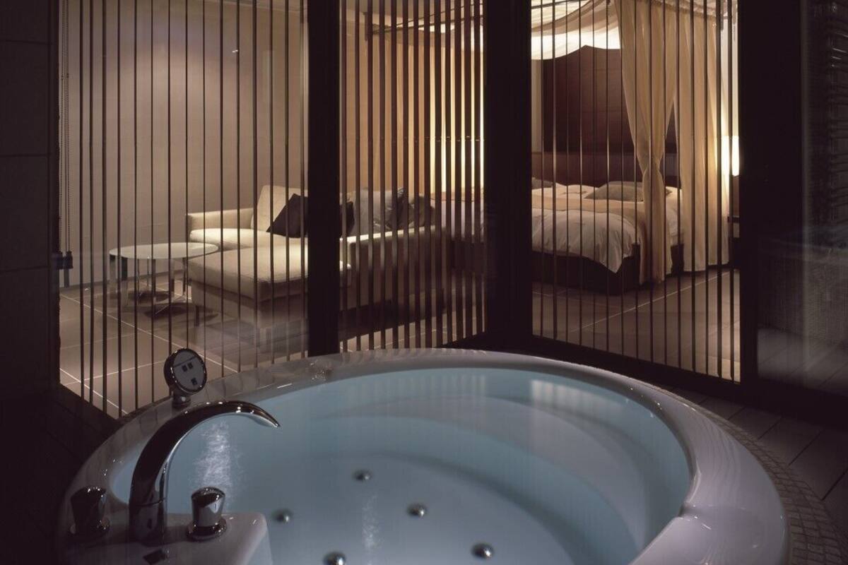 Un baño moderno con una bañera independiente, un espejo redondo y un separador de vidrio.