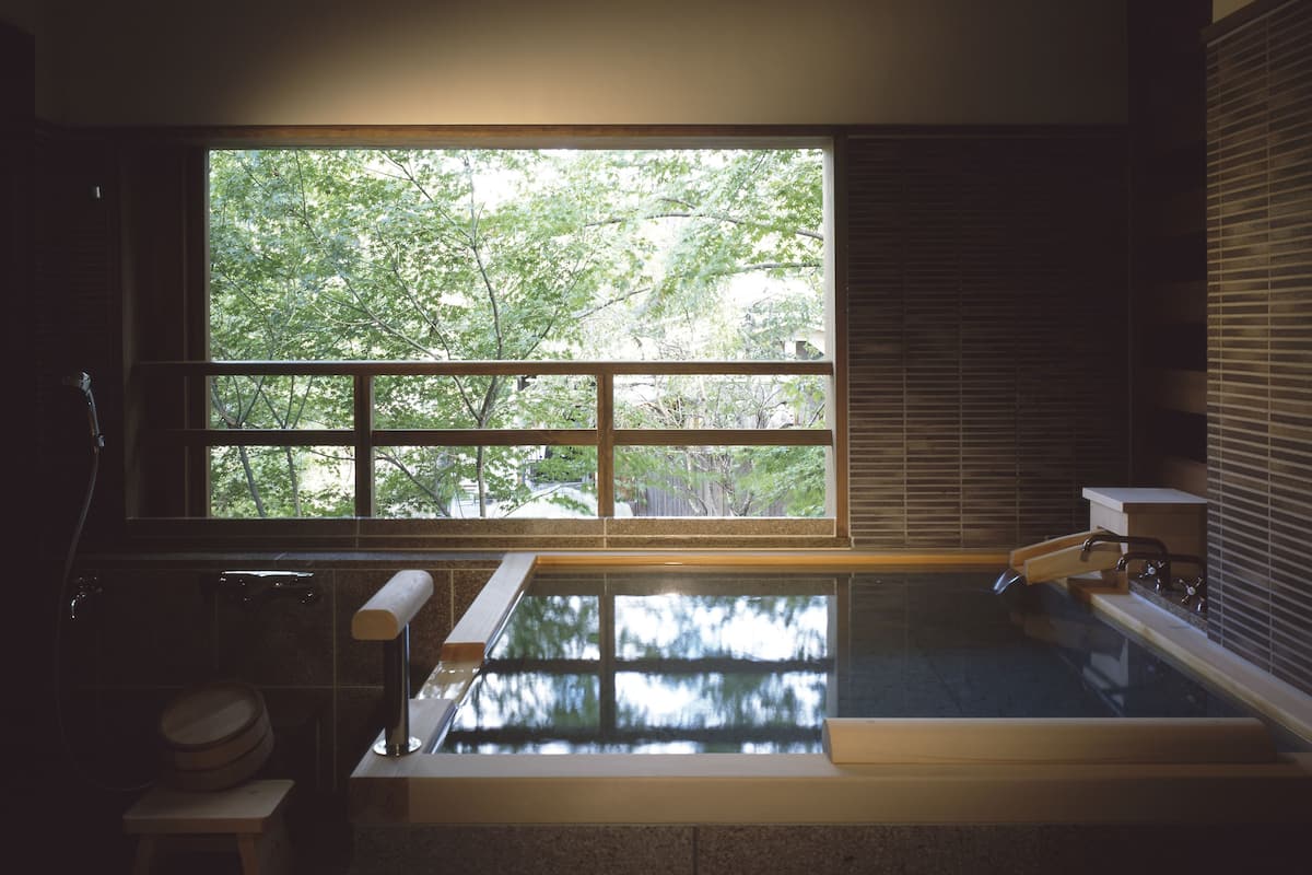 Un baño moderno con un ventanal grande, una bañera y zona de ducha.