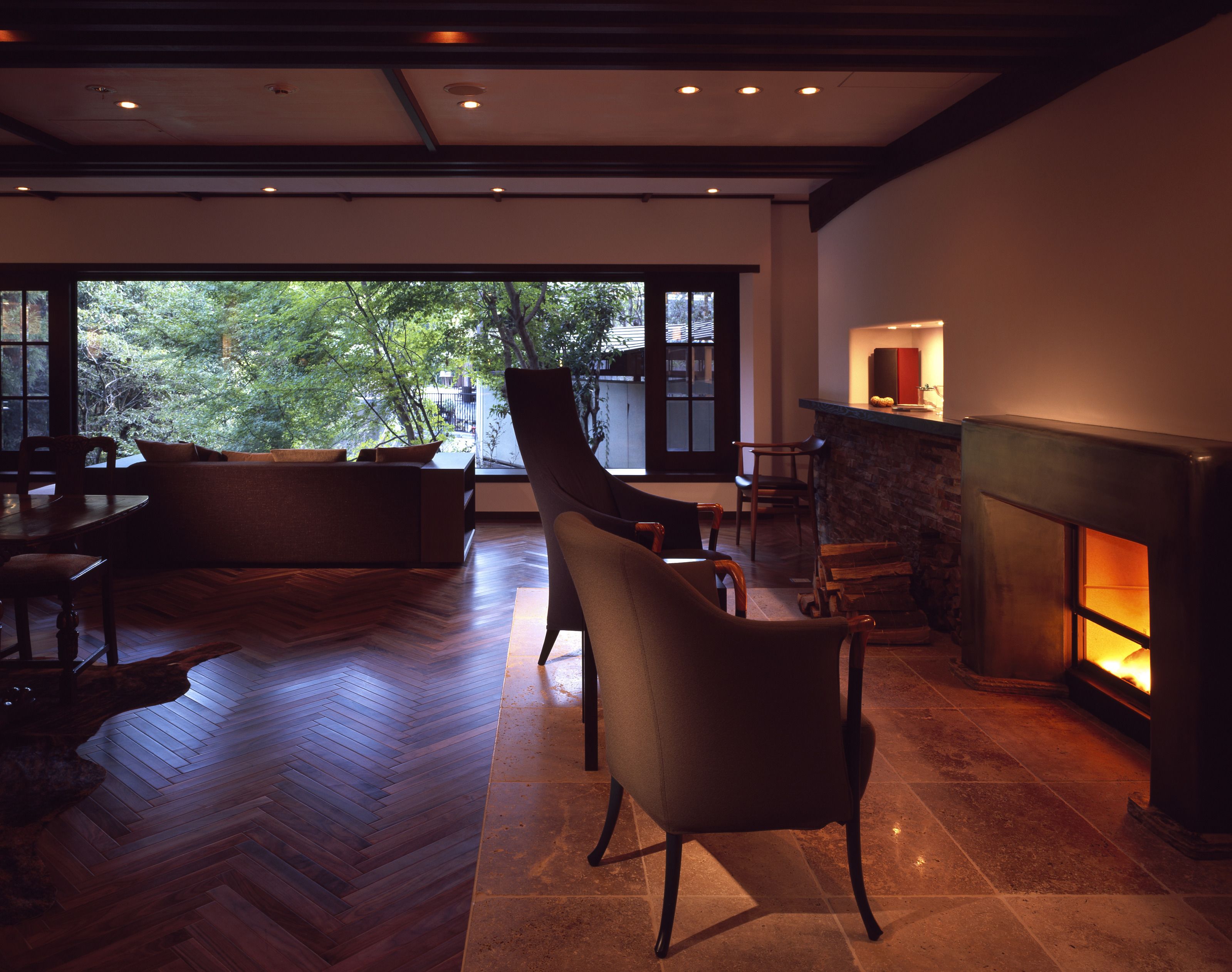 Una sala de estar moderna con chimenea, suelo de madera y un ventanal con vistas a un jardín.
