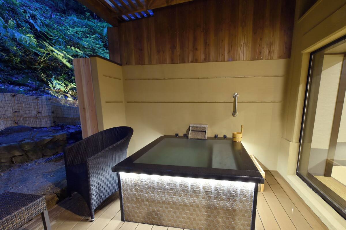 Un jacuzzi con tapa de vidrio, rodeado de paredes de madera y una pared de piedra.