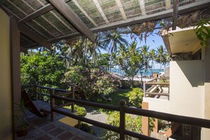 Un balcón con vistas a un jardín tropical, palmeras y una zona de piscina.