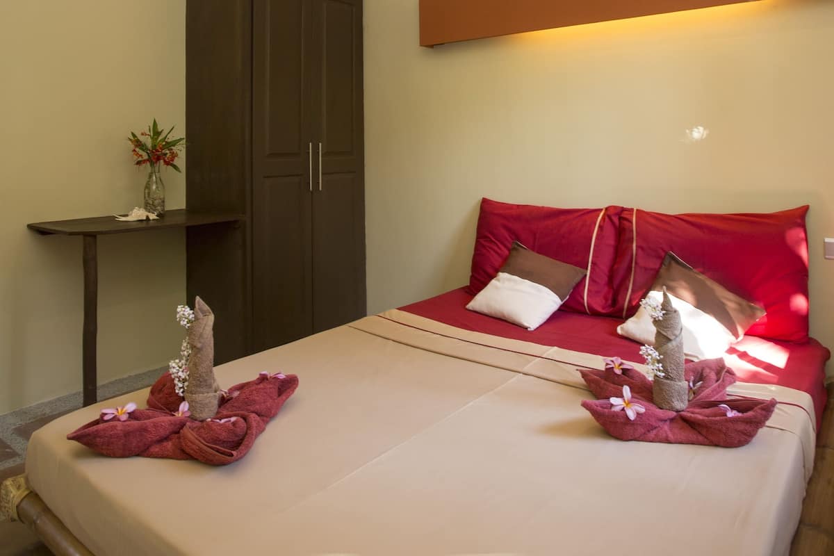 Ein Hotelzimmer mit einem Bett, einem Schrank und einem kleinen Tisch mit einer Vase.