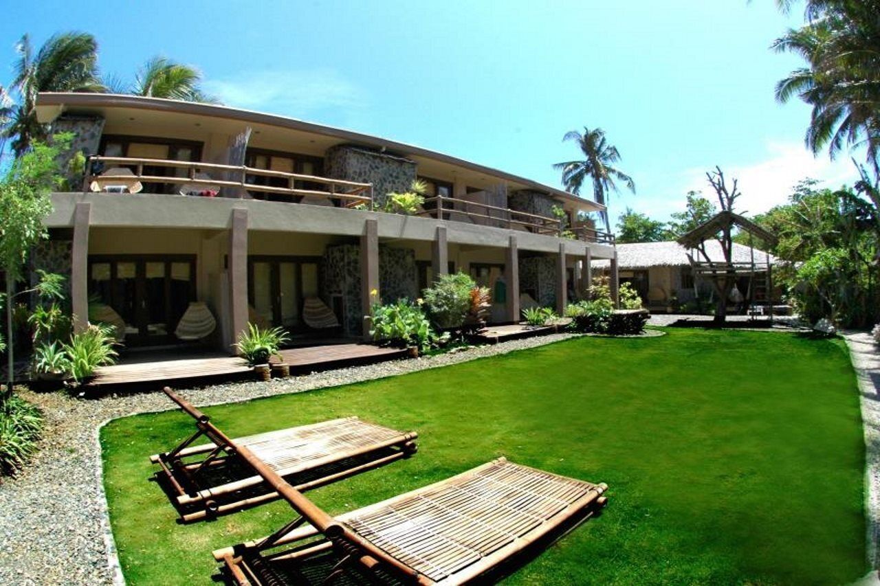 A two-story building with a balcony, a well-maintained lawn, and lounge chairs.