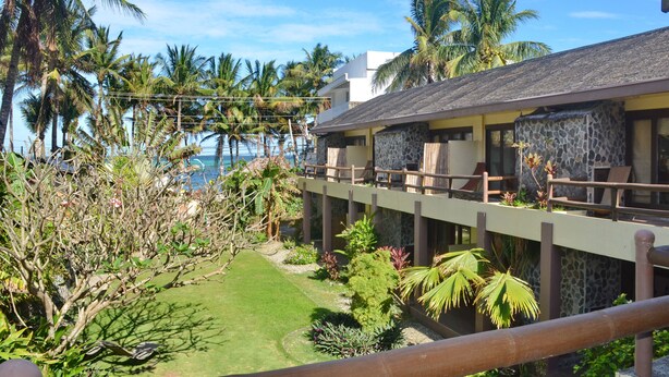 Un hotel con piscina, palmeras y vista al océano.