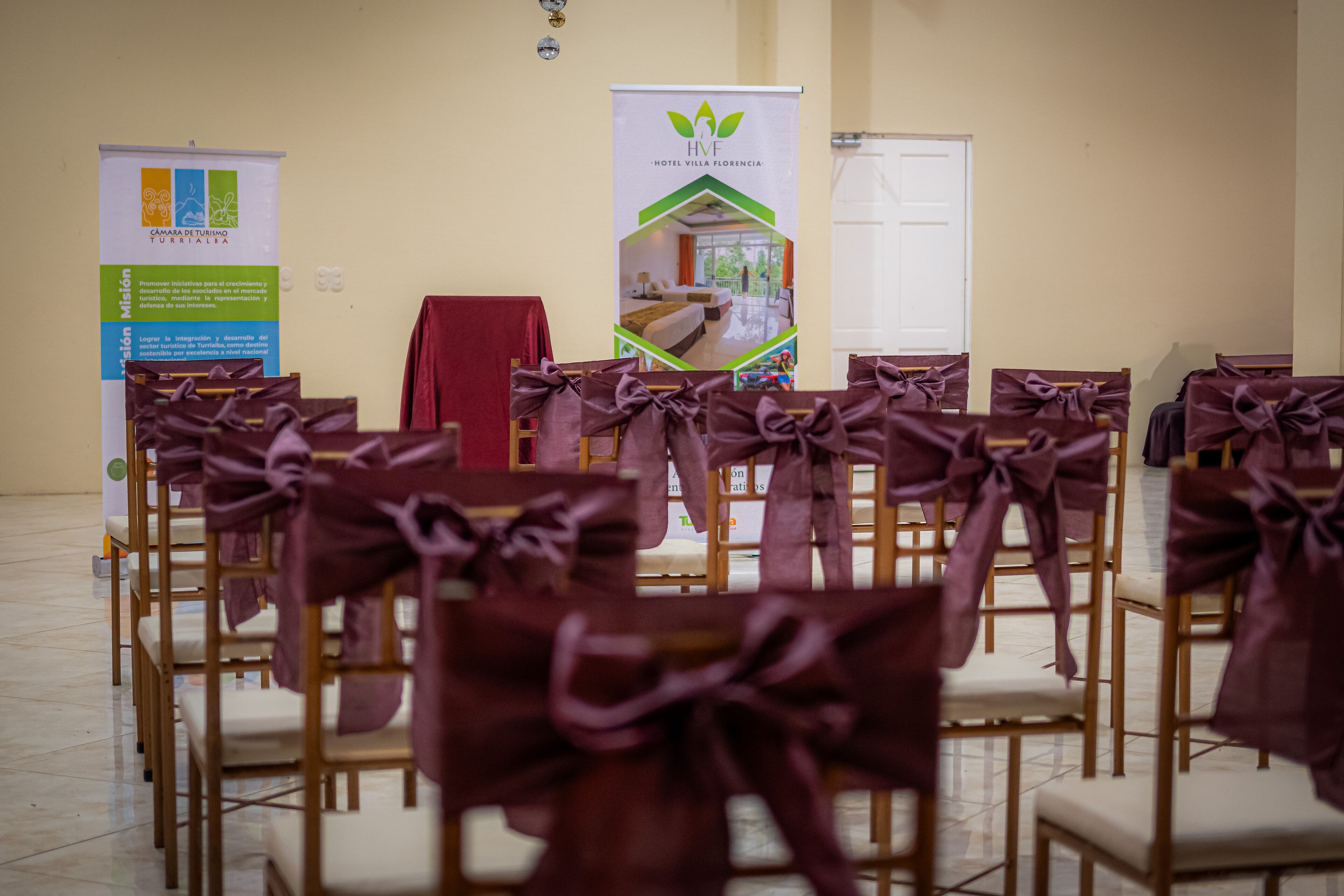 Rows of chairs with purple bows, a banner, and a door in a room.