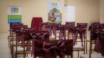 Rows of chairs with purple bows, a banner, and a door in a room.