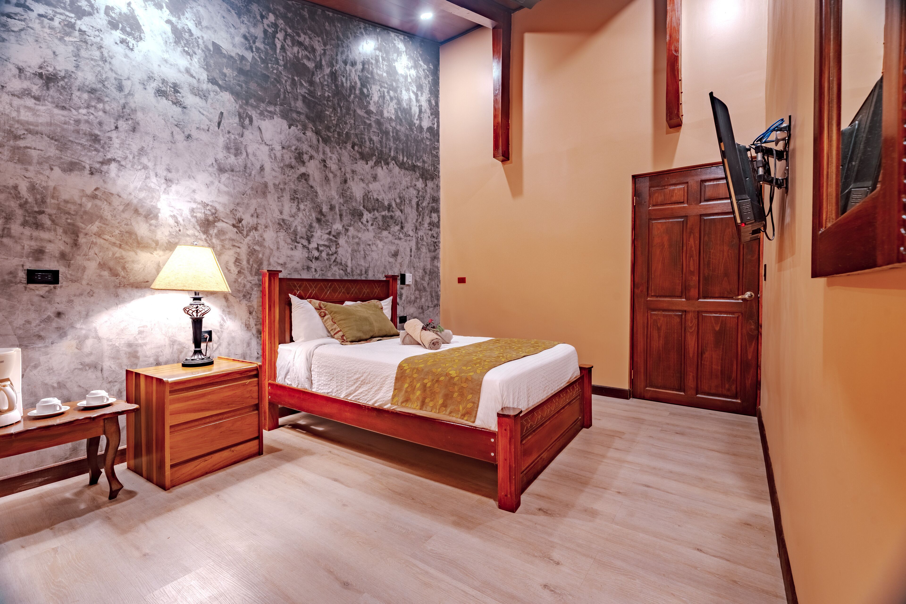 Une chambre à coucher avec un lit en bois, une table de chevet avec une lampe, une commode en bois et une armoire.