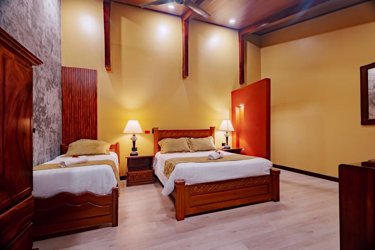 A hotel room with two wooden beds, a marble wall, and a red accent wall.