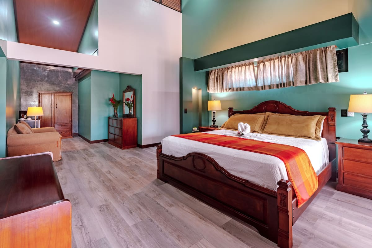 A spacious bedroom with a large bed, wooden headboard, and a view of the city.