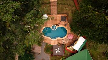 Vue aérienne d’une cour arrière avec une piscine, un espace patio et une petite terrasse.