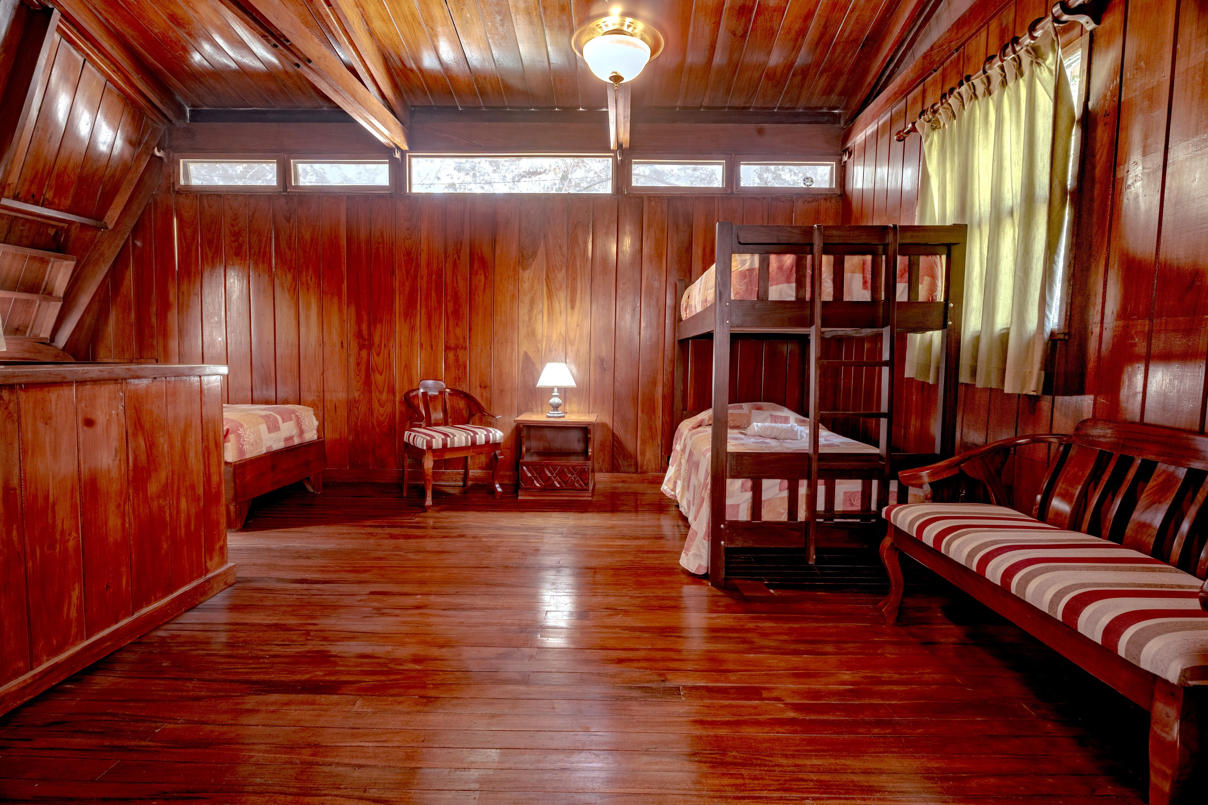A wooden cabin with bunk beds, a small table, and a chair.