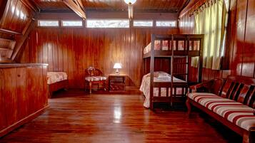 A wooden cabin with bunk beds, a small table, and a chair.