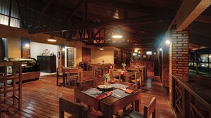 A spacious restaurant with wooden tables and chairs, brick walls, and a high ceiling with exposed beams. - Hotel Villa Florencia (Turrialba)