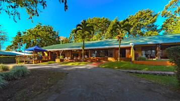 A building with a green roof, outdoor seating, and a covered area with a blue canopy.