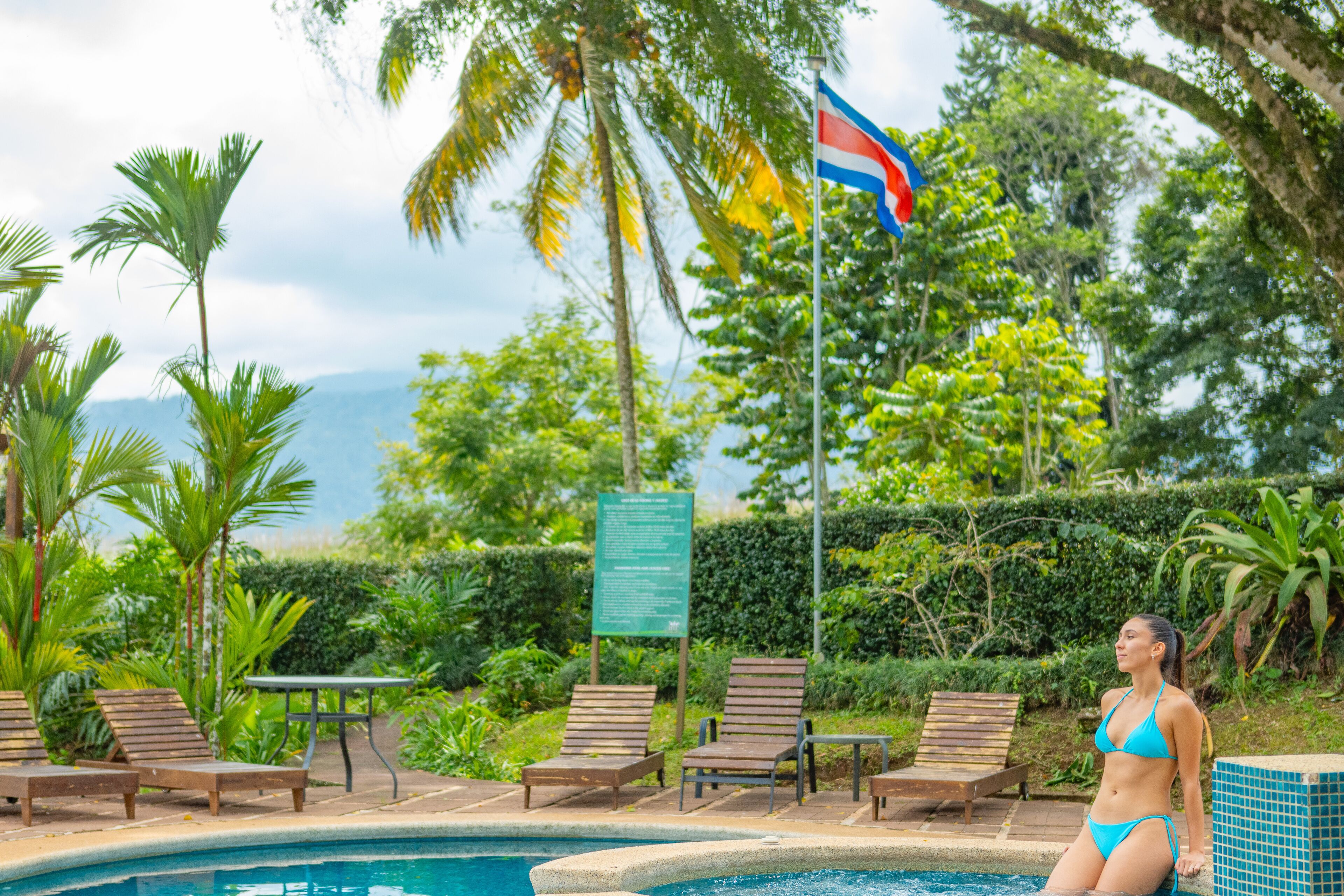 Zona de piscina con sillas de descanso y una bandera.