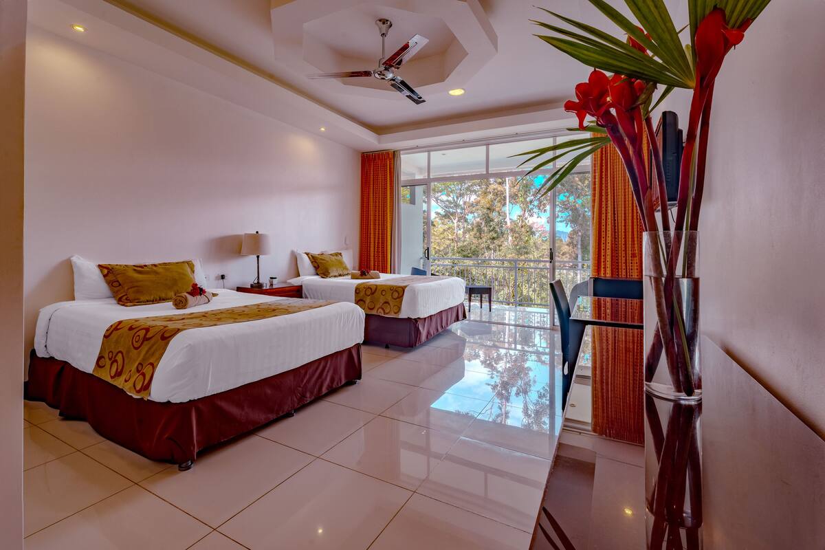 A hotel room with two beds, a balcony, and a large window with curtains.