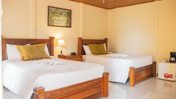 A hotel room with two wooden beds, white linens, and a single nightstand with a lamp.