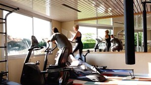 A gym with treadmills, a mirrored wall, and large windows.