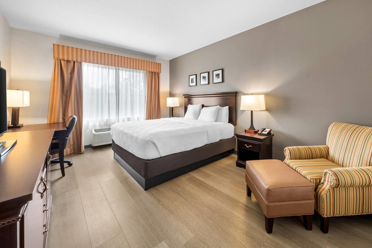 Een hotelkamer met een bed, bureau, stoel en poef.