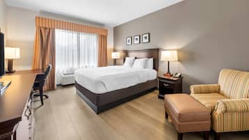A hotel room with a bed, desk, chair, and ottoman.