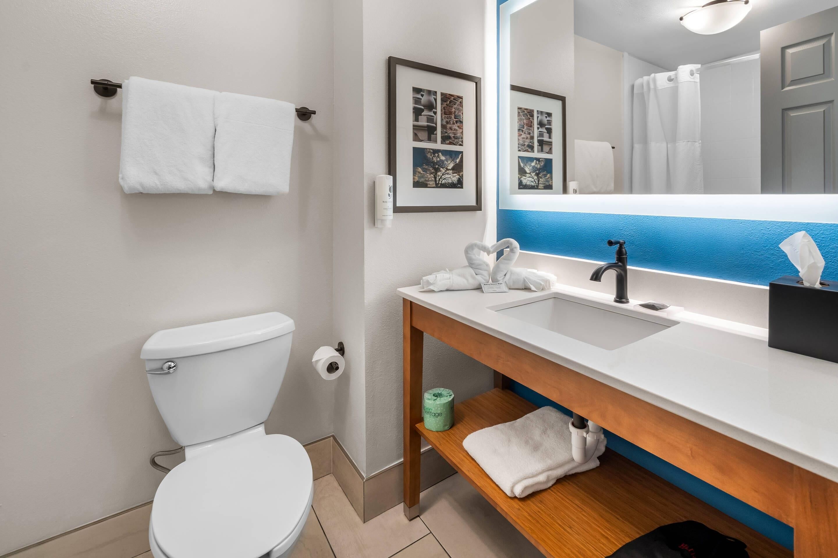 A modern bathroom with a white toilet, a sink with a mirror, and a towel rack.