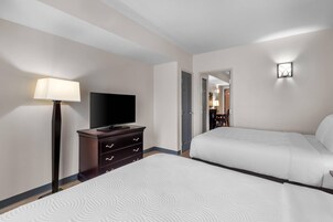 Una habitación de hotel con una cama, televisión, cómoda y lámpara.