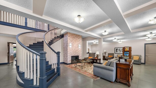 A spacious living area with a spiral staircase, a fireplace, and a modern fireplace mantel. - Country Inn & Suites by Radisson, Port Orange-Daytona, FL (Port Orange)