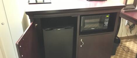 A kitchenette with a refrigerator, microwave, coffee maker, and a small sink.