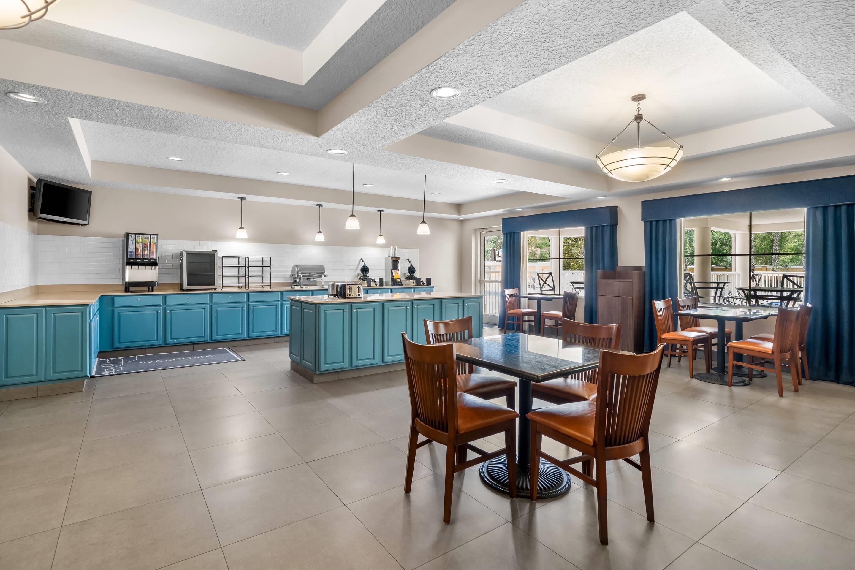 A spacious kitchen with blue cabinets, a central island, and a dining area with wooden chairs and a table.
