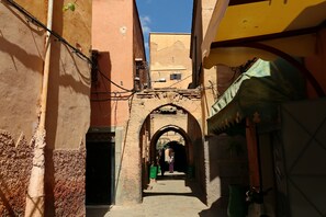 Une ruelle étroite, surmontée d’une arche en pierre, mène à l’entrée d’un immeuble.