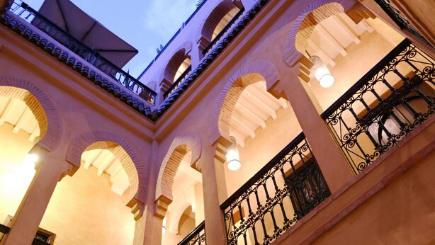 A courtyard with arches and a balcony. - Riad Marrakiss (Marrakech)