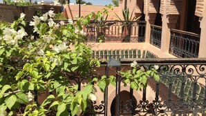 A courtyard with a wrought iron fence, a pergola, and a building with arches. - Riad Marrakiss (Marrakech)