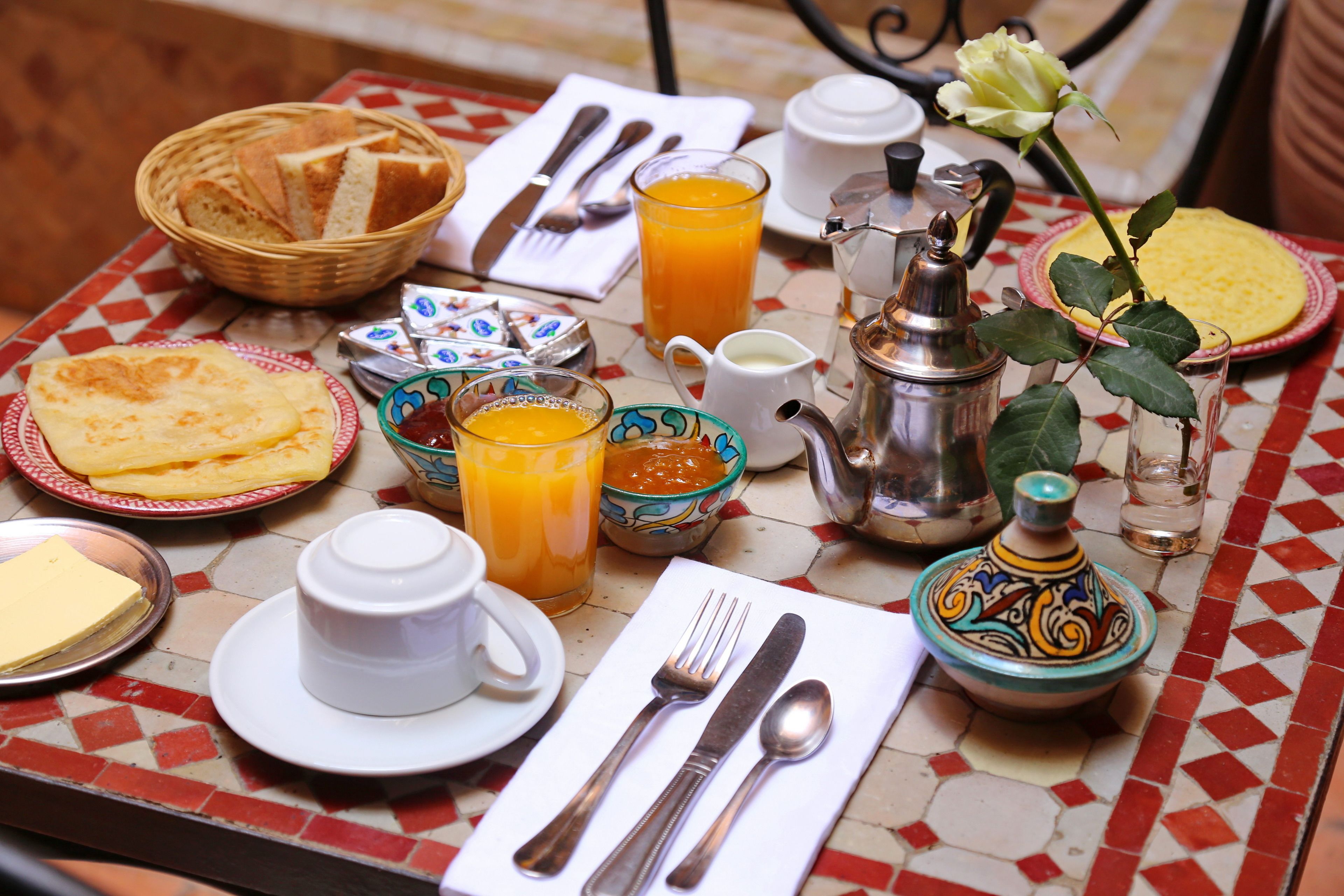 A breakfast table with various breakfast items, including bread, eggs, juice, and a teapot.